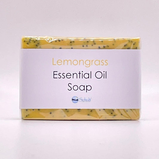 bar of natural lemongrass soap, yellow with blue poppyseeds. front view showing paper label